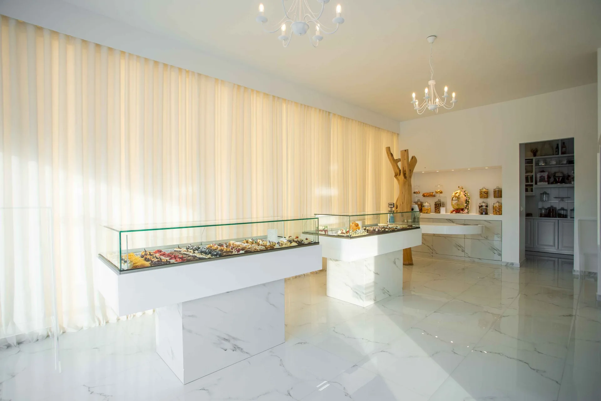 Bright interior of Epoca Patisserie with marble display counters and chandeliers