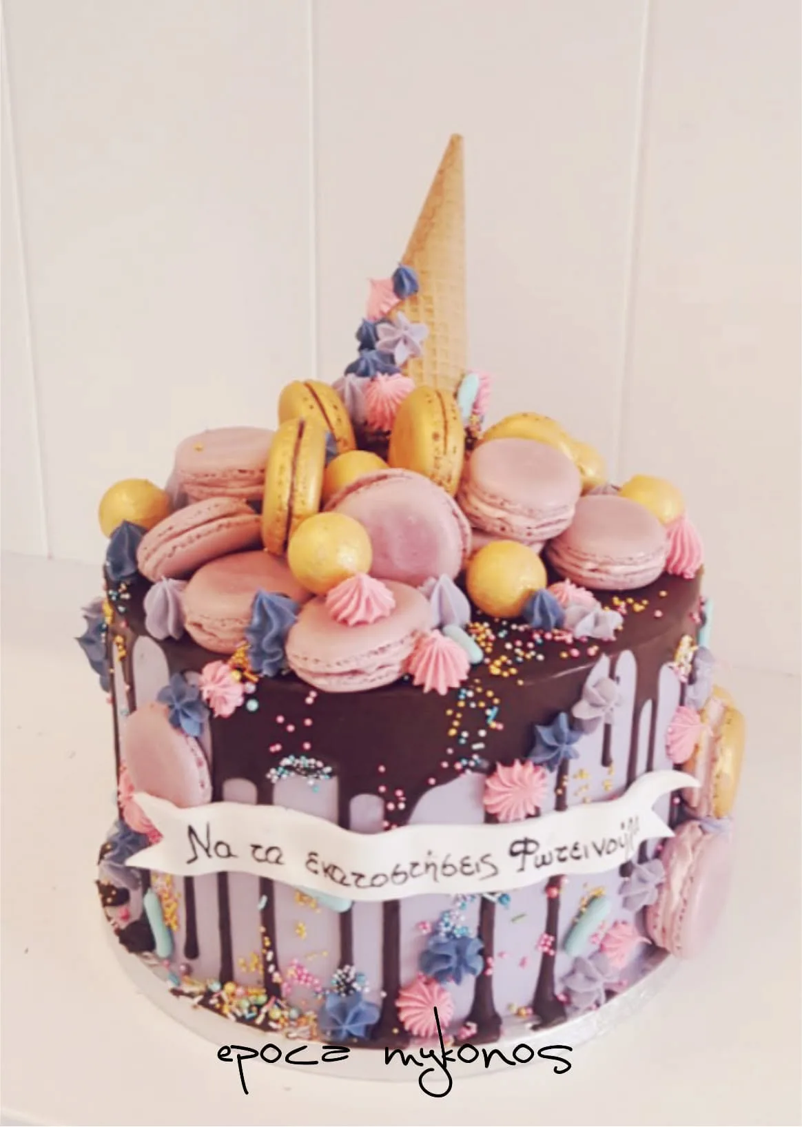 Chocolate drip birthday cake topped with pink macarons, meringue kisses and a hand-written greeting