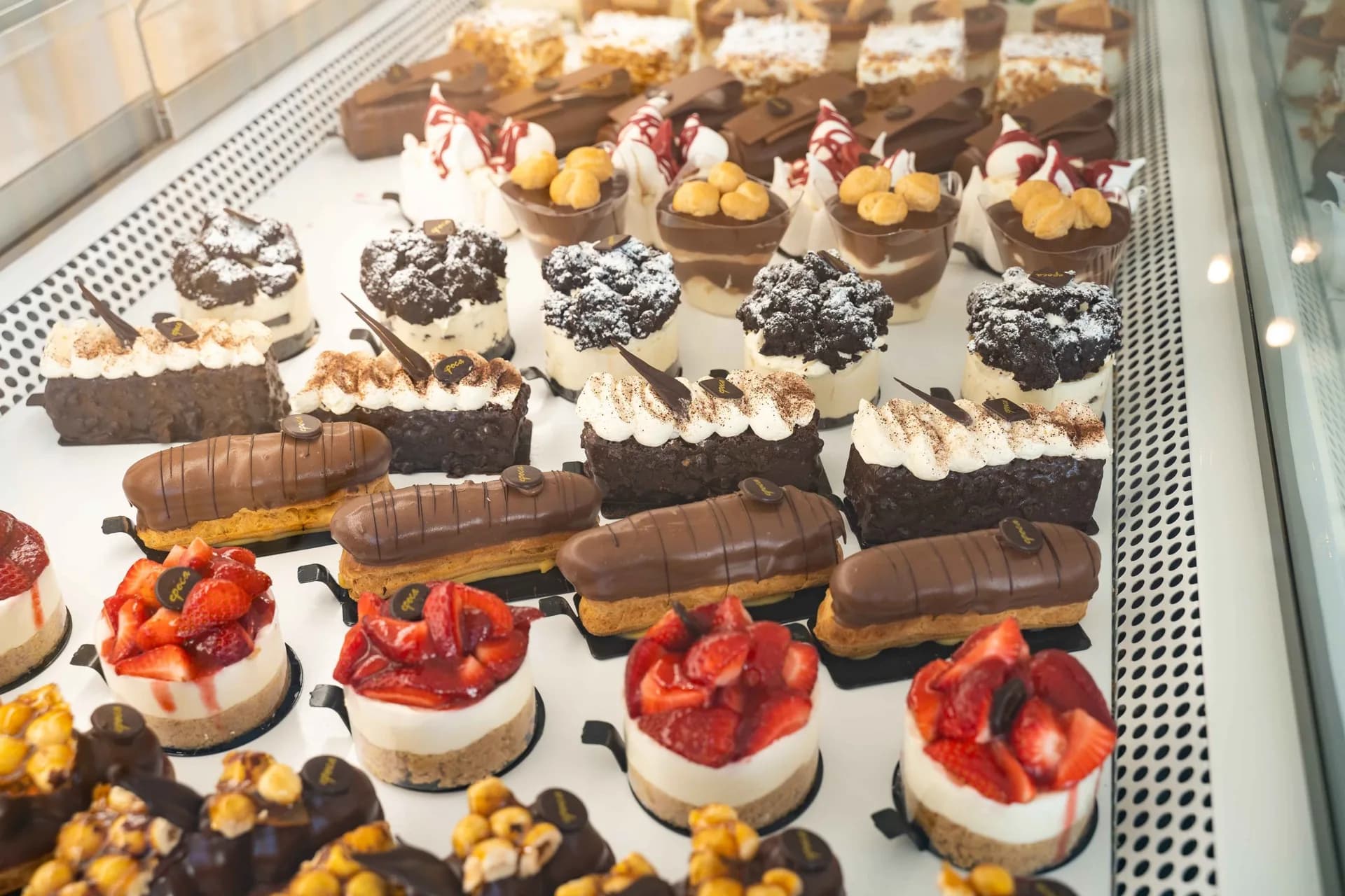 Fresh éclairs, strawberry cheesecakes and chocolate pastries in the patisserie display